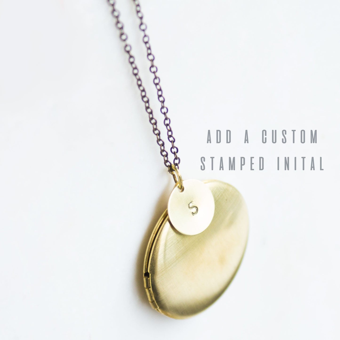 The large modern brass locket with an initial charm added to it.